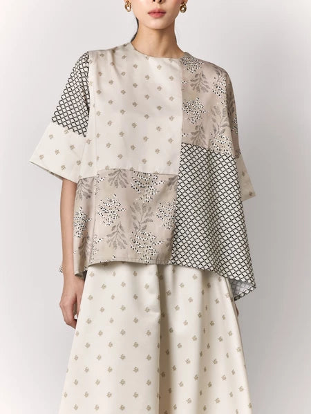 Woman wearing a two-piece outfit with a patterned blouse and skirt by Studio Tui on a white background