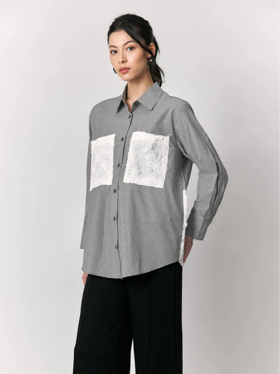 Woman wearing a black striped shirt by Studio Tui with white lace pockets design on a plain background