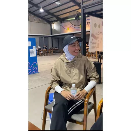 Person wearing latte-colored track jacket by Abame in an indoor setting