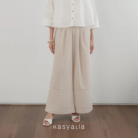 Person wearing a white shirt and beige wide-leg striped pants on a plain background with 'kasyalia' branding.