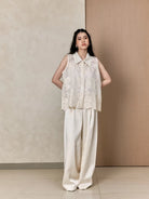 Woman wearing a sleeveless embroidered vest by Studio Tui and wide-leg pants against a neutral background