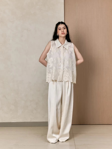 Woman wearing a sleeveless embroidered vest by Studio Tui and wide-leg pants against a neutral background