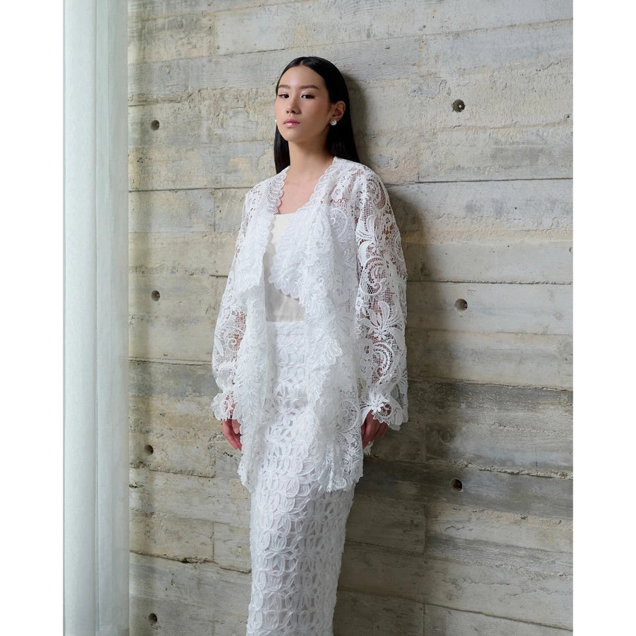 Woman in a white lace vest by Kasa Heritage standing against a textured wall.