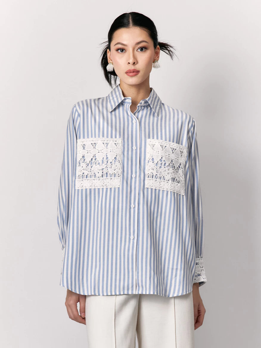 Woman wearing a blue and white striped shirt by Studio Tui with lace details on a plain background