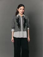 Woman wearing a black and white striped shirt with floral patterns by Studio Tui on a gray background