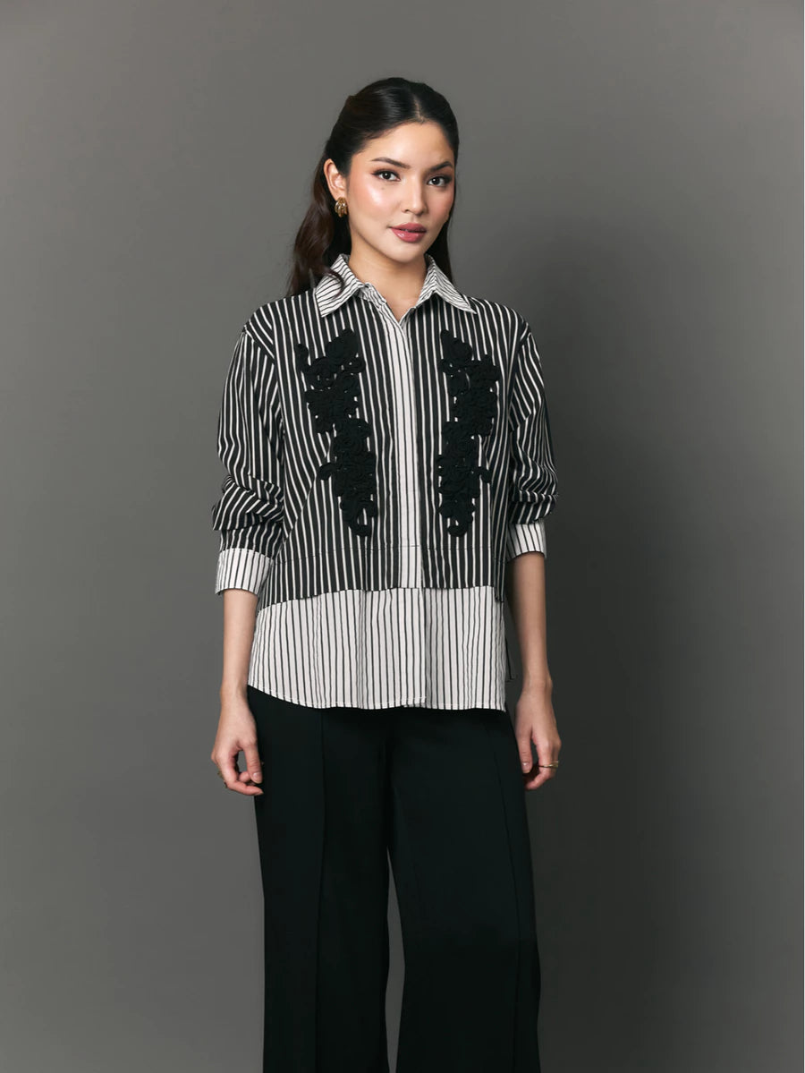 Woman wearing a black and white striped shirt with floral patterns by Studio Tui on a gray background
