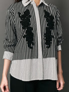 Black and white striped shirt with black floral appliqués by Studio Tui on a gray background