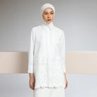 Woman wearing a white shirt by Hijabchic with lace details against a neutral background