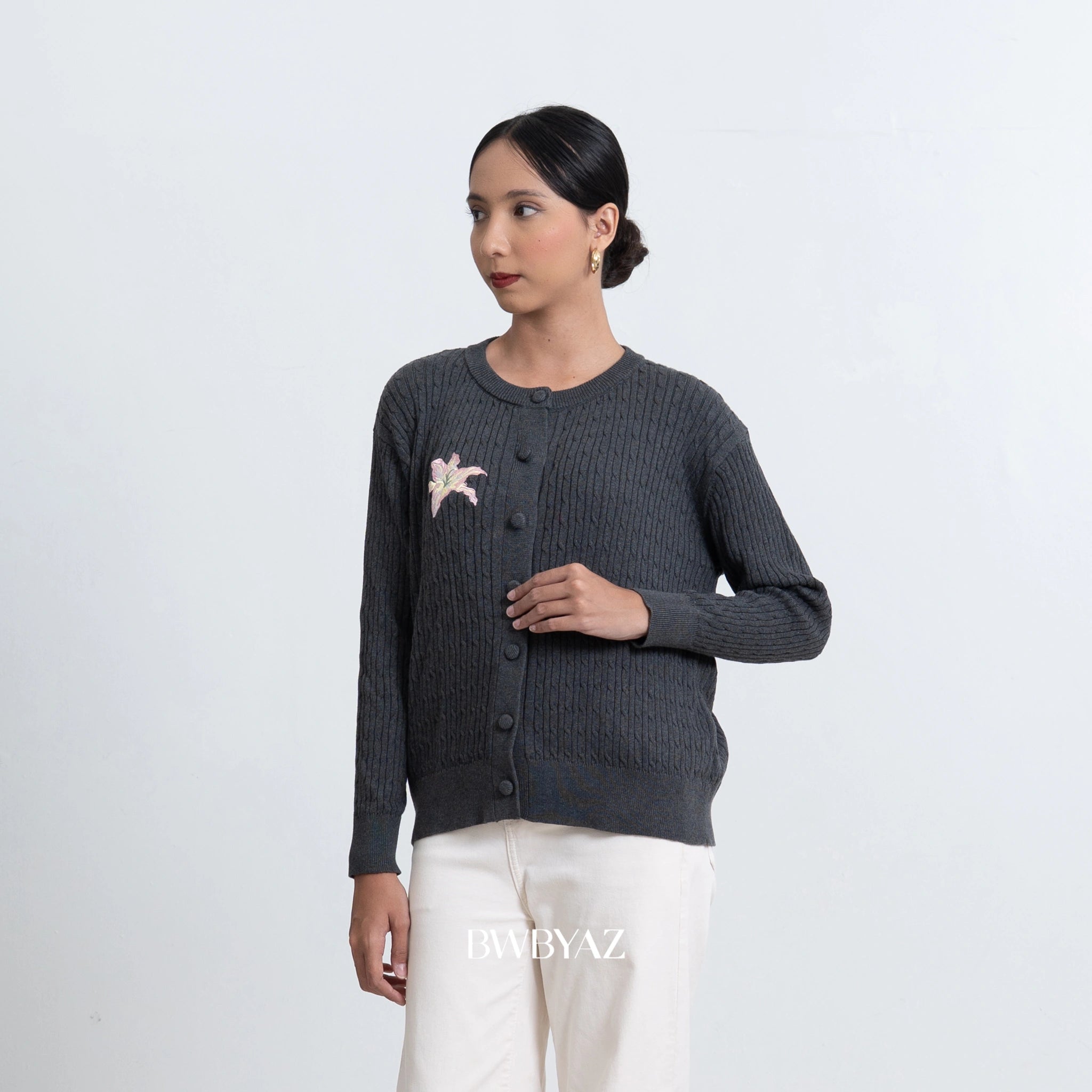 Woman wearing a dark gray cardigan by BWBYAZ with a floral design on a white background