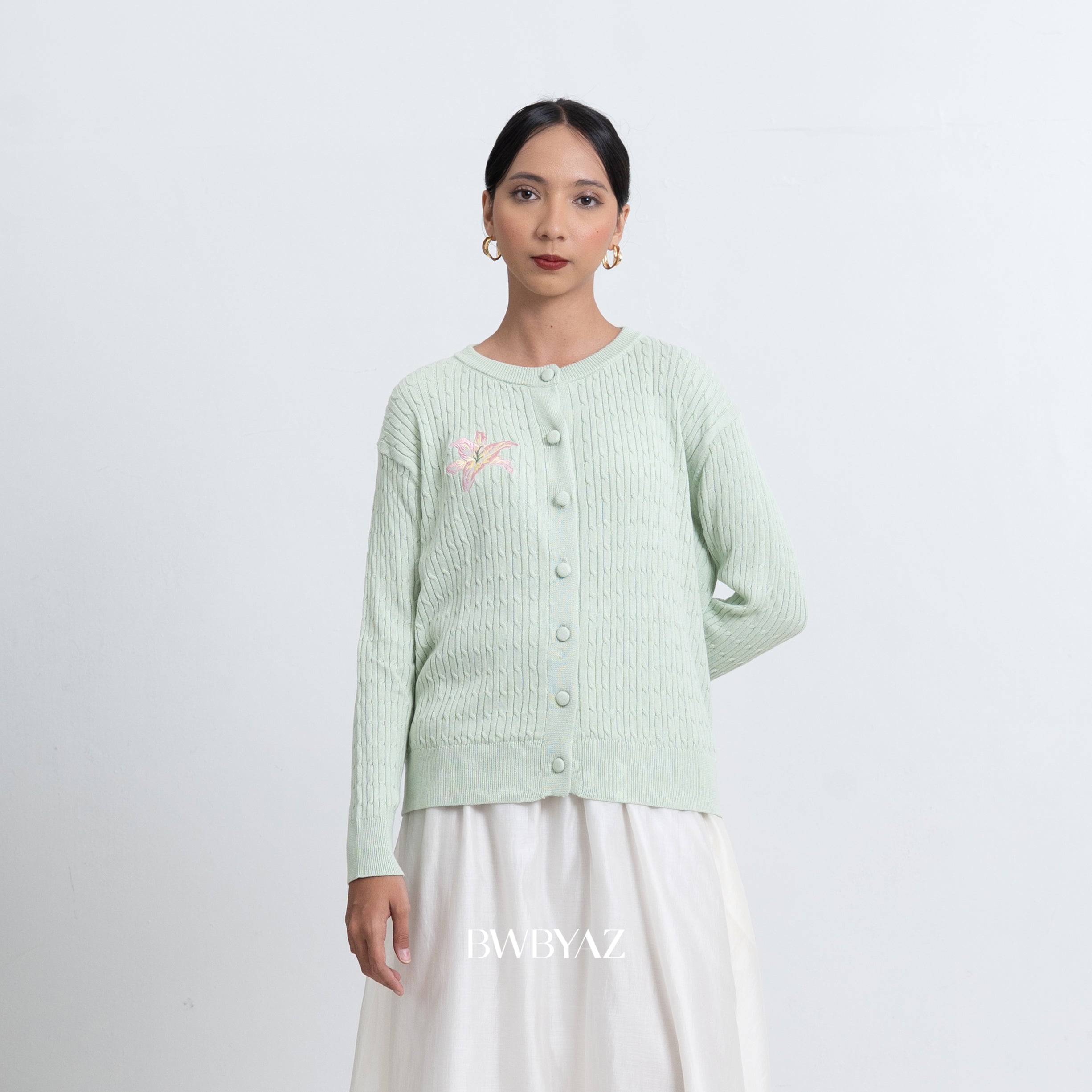 Woman wearing a light green cardigan by BWBYAZ with floral embroidery on a white background