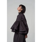 Person wearing a black layered blouse by Yestoday and skirt set against a plain background