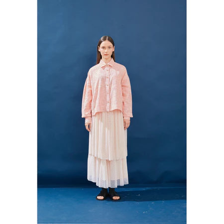 Woman wearing a pink blouse and pink layered skirt by Yestoday against a blue background