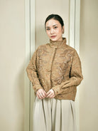Woman wearing a patterned brown outer by Studio Tui against a plain background