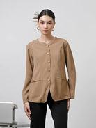 A woman wearing a brown long-sleeved blouse with gold front buttons by Kasa Heritage, paired with blue jeans.