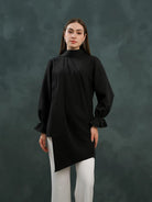 Person wearing a black blouse by Kasa Heritage with a high collar against a dark background