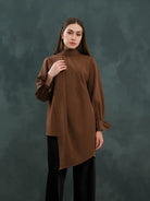 Woman wearing a brown long-sleeve blouse by Kasa Heritage against a dark background