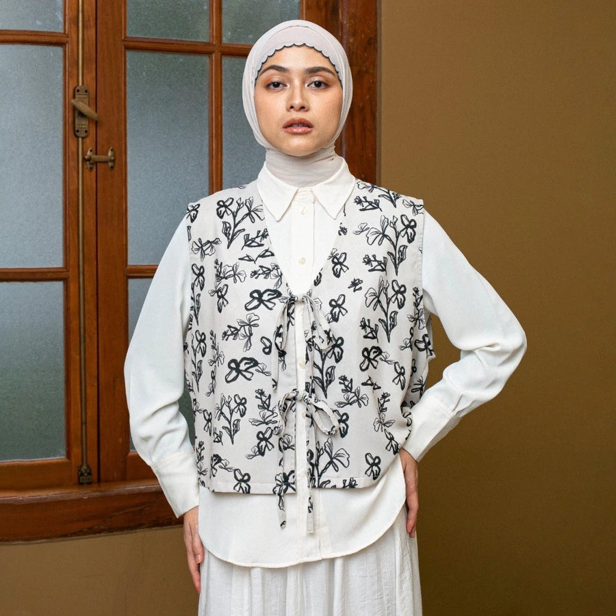 Woman wearing a cream-colored with a black floral patterned vest by Lozy Hijab in front of a window.