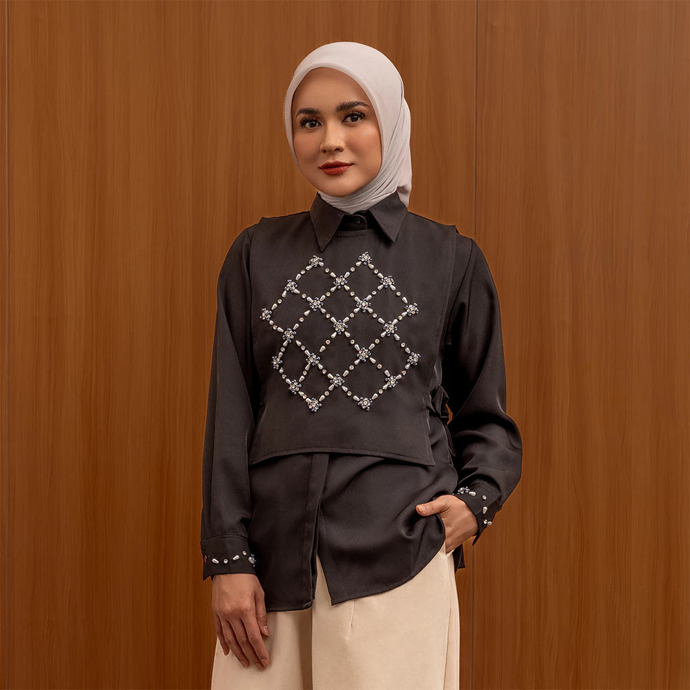Woman wearing a black shirt by Jenna & Kaia with a geometric pattern against a wooden background