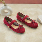 Maroon suede flat shoes with a bow by Dianable on a beige surface