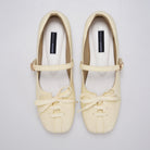 A pair of butter yellow Mary Jane ballet flatshoes by Cekhas with matching ribbon bows and small gold-tone buckle details, displayed on a light gray background.