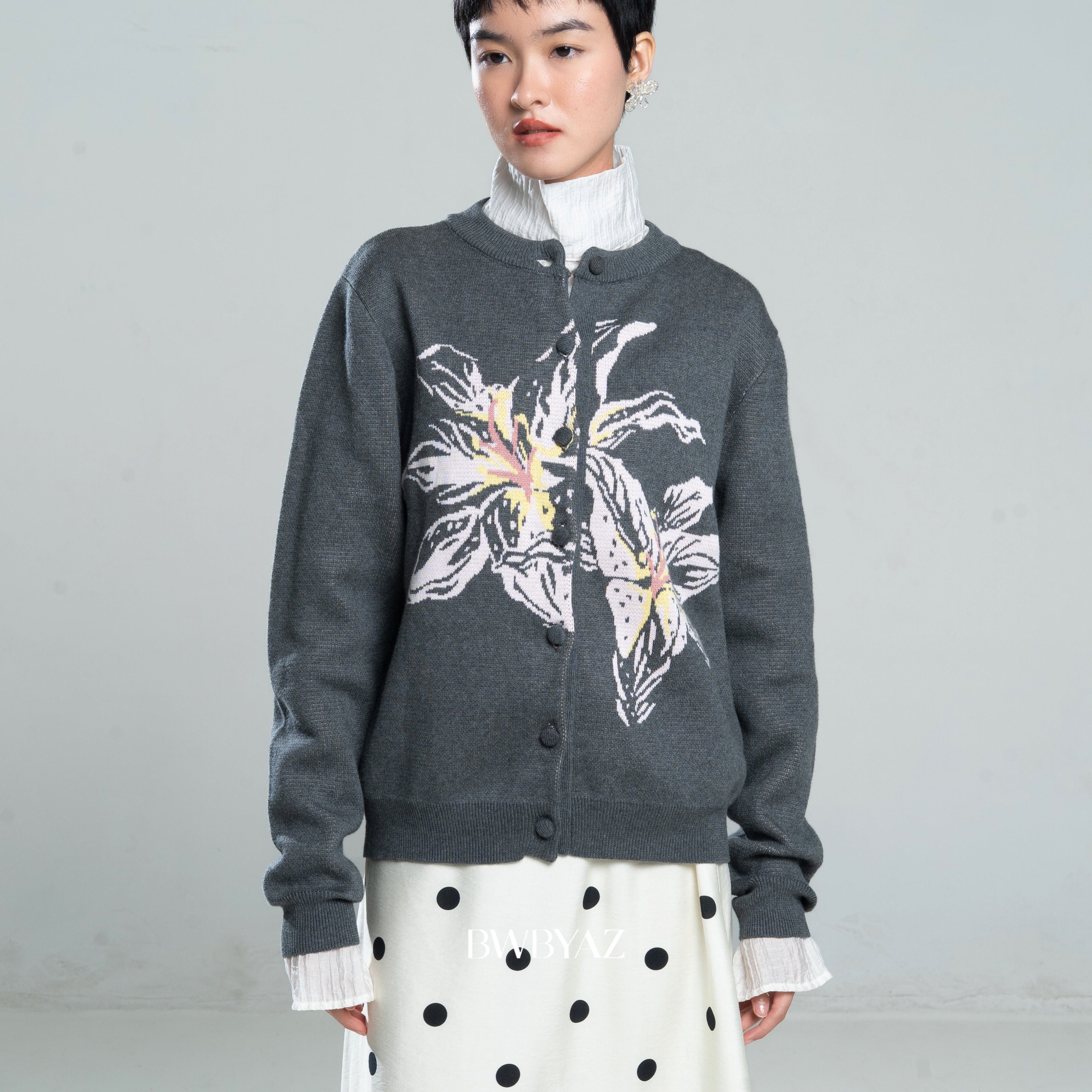 Person wearing a dark gray cardigan by BWBYAZ with floral design on a plain background