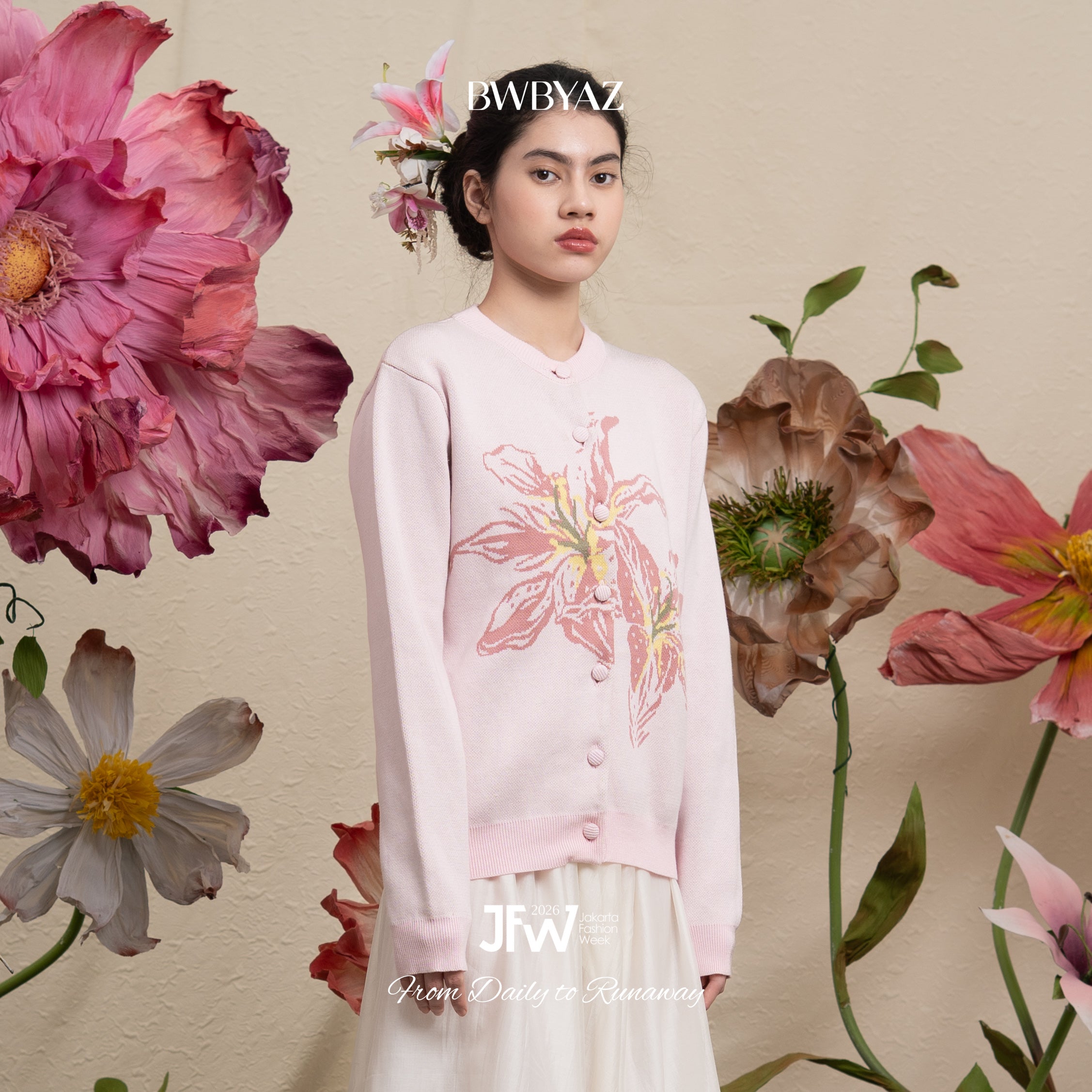 Woman wearing a light pink cardigan by BWBYAZ with floral design against a floral background