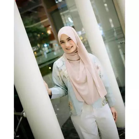 Woman wearing a light blue-colored top with floral design by Haidee Orlin in an indoor setting