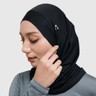 Woman wearing a black sport hijab by HIA on a light gray background