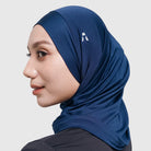 Woman wearing a navy sport hijab with a logo by HIA on a light gray background