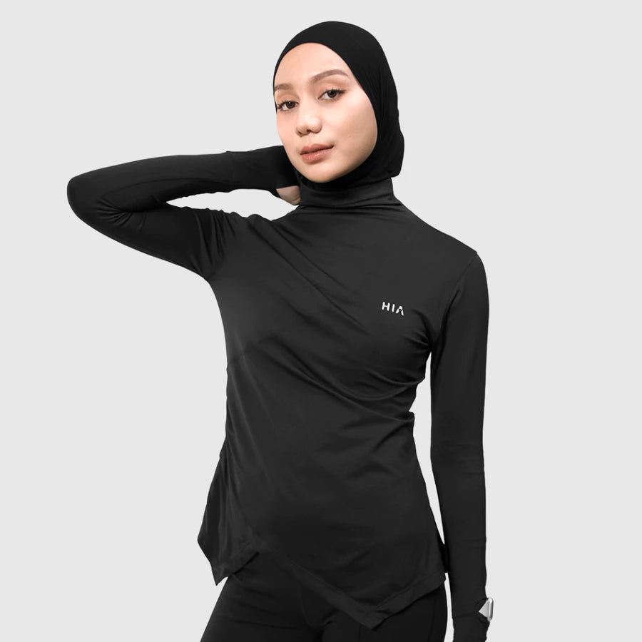 Person wearing a black long-sleeve athletic top by HIA with hijab on a light gray background