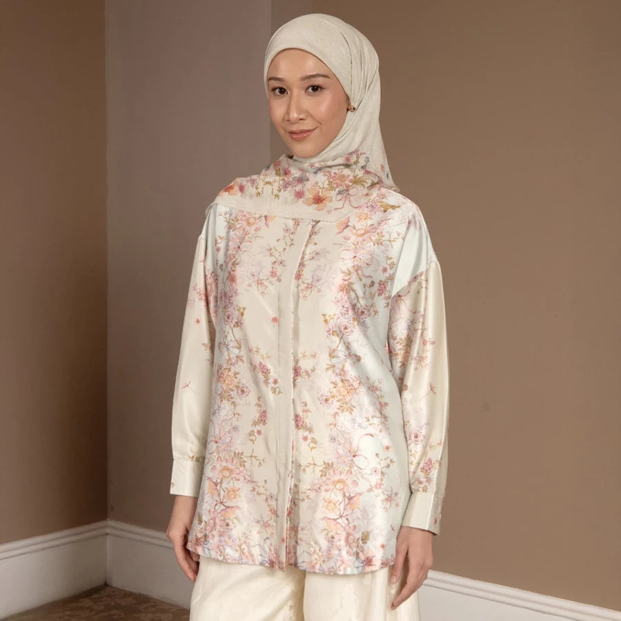 Woman wearing a floral shirt by Hijabchic and hijab against a plain wall