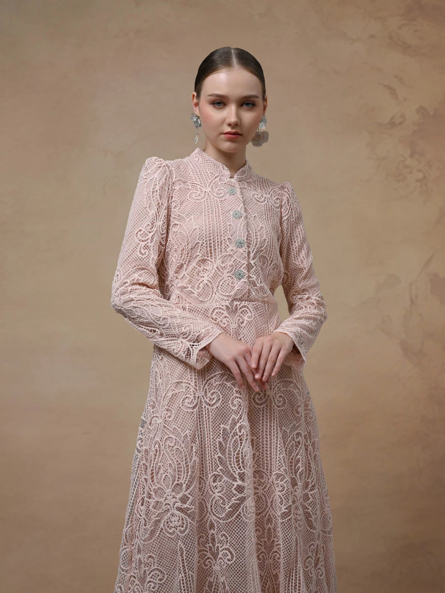 Woman wearing a pink lace maxi dress by Kasa Heritage against a beige background