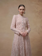 Woman wearing a pink lace maxi dress by Kasa Heritage against a beige background