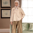 Woman wearing a beige shirt by Hijabchic with a hijab in a living room setting