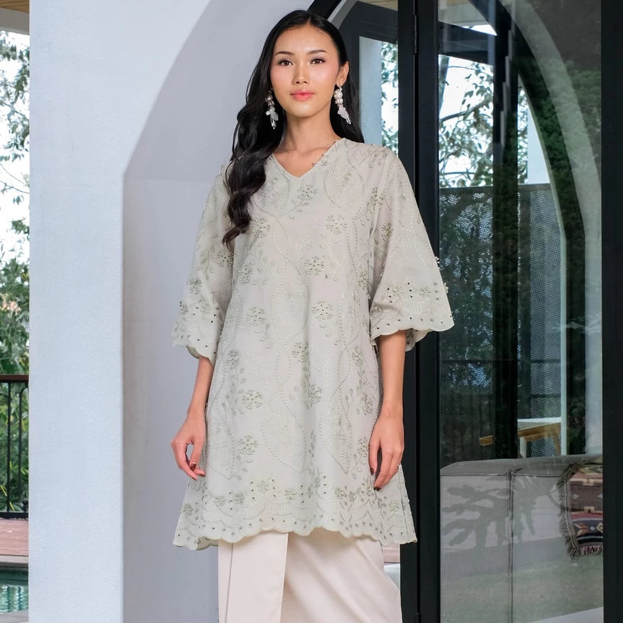 Woman wearing a sage green tunic by Holy Peony with floral embroidered.

Seorang wanita mengenakan tunik berwarna hijau sage dari Holy Peony dengan hiasan bordir bunga.