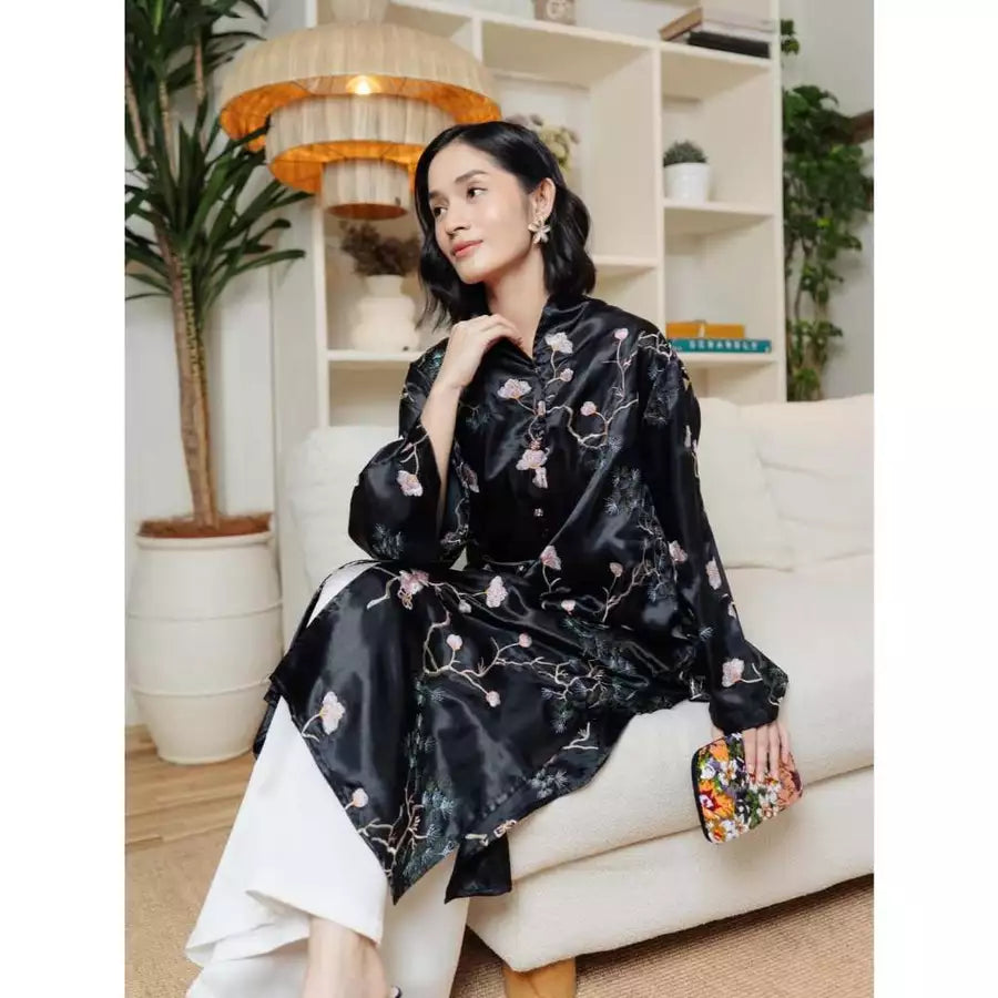 Woman in a black floral tunic by Haidee Orlin sitting on a white couch in a home setting.

Seorang wanita mengenakan tunik bermotif bunga berwarna hitam karya Haidee Orlin sedang duduk di sofa putih di dalam sebuah rumah.