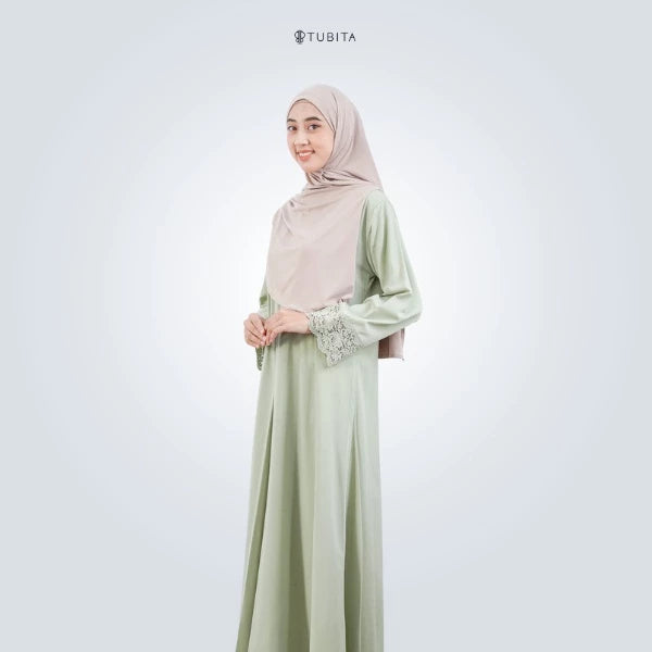 Woman wearing a light green abaya with a matching hijab on a white background, featuring the brand 'TUBITA'.