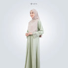 Woman wearing a light green abaya with a matching hijab on a white background, featuring the brand 'TUBITA'.