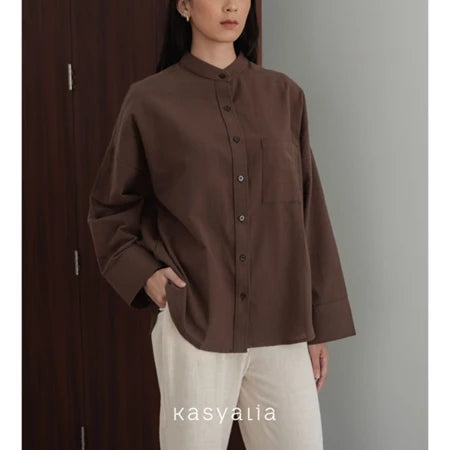 Person wearing a brown shirt with a neutral background, featuring the brand 'kasyalia'.