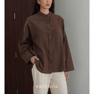 Person wearing a brown shirt with a neutral background, featuring the brand 'kasyalia'.