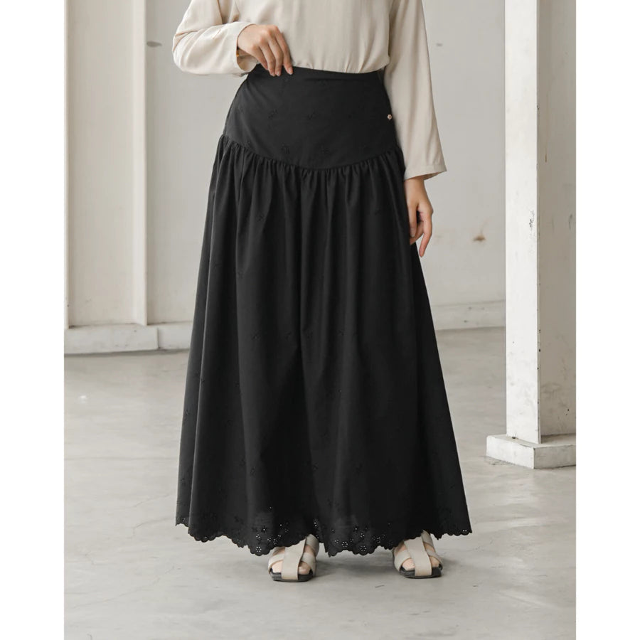 Person wearing a black skirt by Mistyvori and beige top in a minimalistic room.