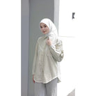 Woman wearing a yellow striped shirt by Abame and hijab against a plain background