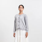 Woman wearing a light gray cardigan by BWBYAZ with a white background