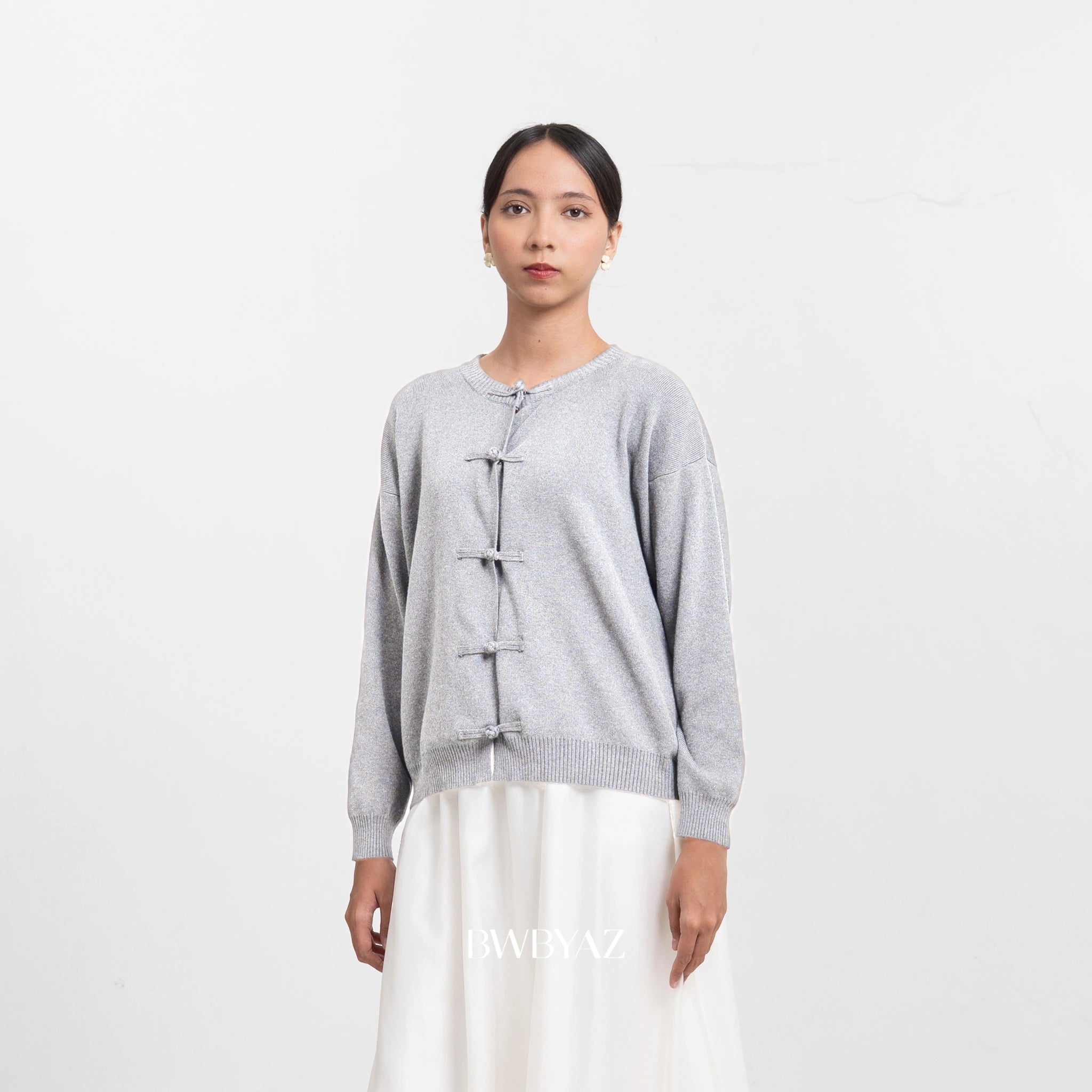 Woman wearing a light gray cardigan by BWBYAZ with a white background