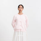 Woman wearing a light pink cardigan and white pants on a white background with 'BWBYAZ' branding.