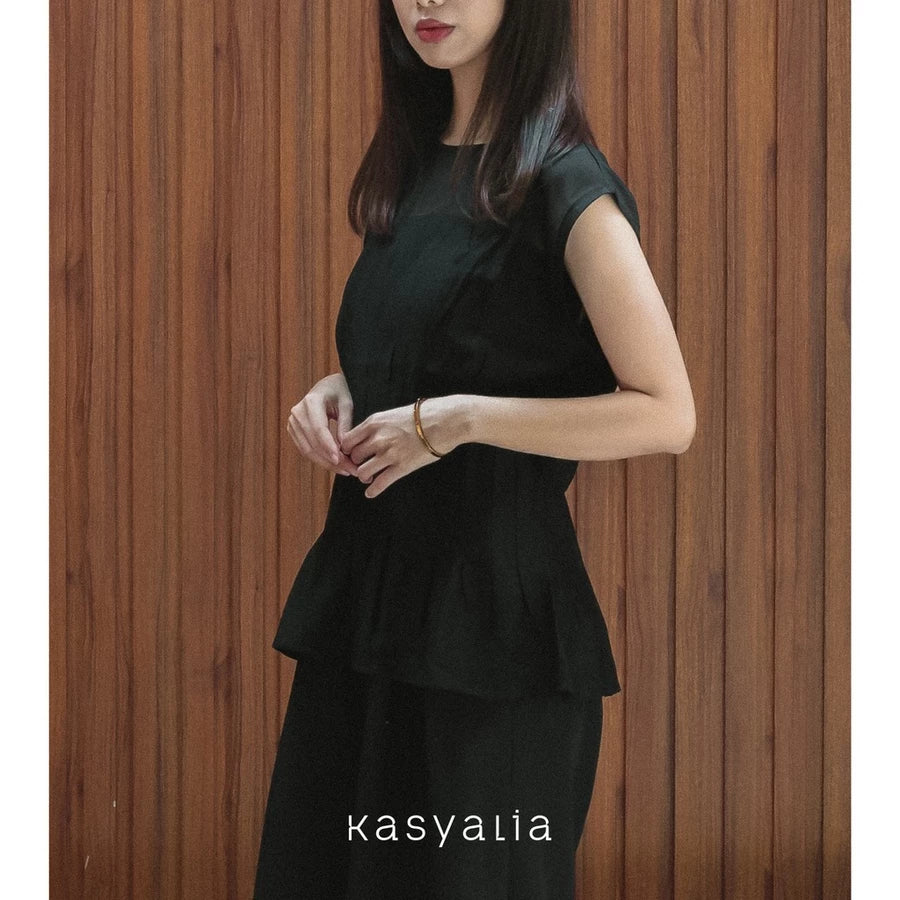 Woman wearing a black blouse against a wooden background with 'kasyalia' branding.
