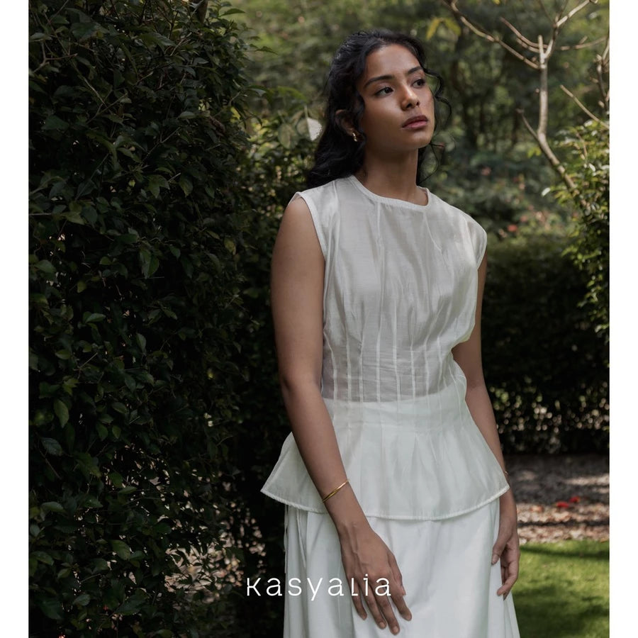 Woman wearing a cream blouse standing in a garden with 'kasyalia' branding.