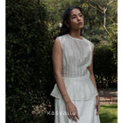 Woman wearing a cream blouse standing in a garden with 'kasyalia' branding.