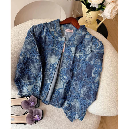 Dark jeans floral-patterned jacket from Haidee Orlin on a chair with a pair of shoes and a vase in the background.