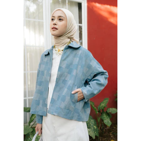 Woman wearing a light blue checkered denim jacket from Haidee Orlin with a white background